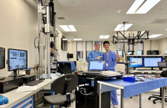 Two researchers in scrubs in a laboratory fitted with testing frames and workstations
