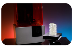 A desktop stereolithography 3D printer beside a freshly printed vertebral model